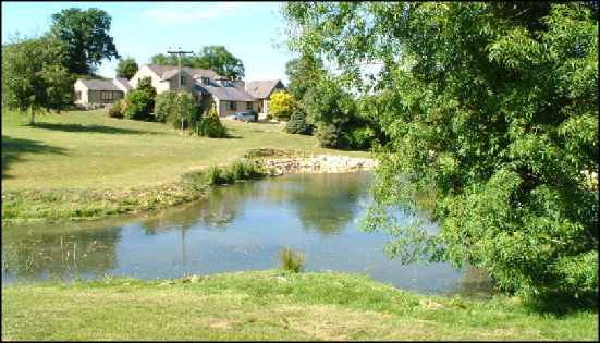 View across the garden pond looking at the farm house in late spring